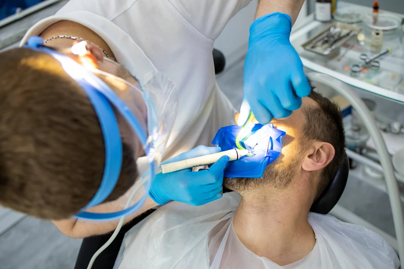 Practitioner male dentist drilling tooth to patient in dental studio